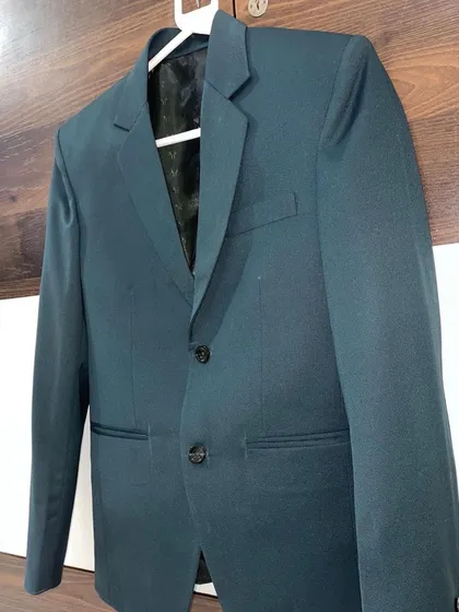 A dark teal single breasted blazer hanging in my workshop. You can see the clean lines and quality finish I provide on every garment.