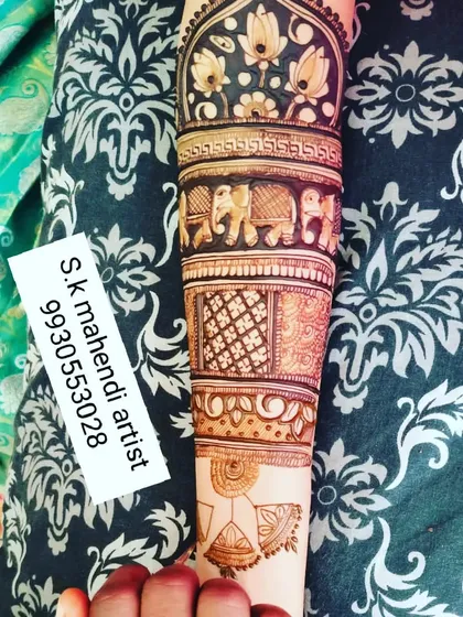 A close-up of an arm design showing bands of different patterns. You can see elephants, lotuses, and geometric jaali work, demonstrating a variety of techniques.