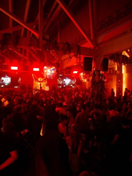 A wide shot of the club bathed in red light, capturing the intense and moody atmosphere of the party.