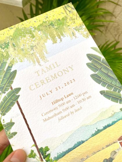 Holding the Tamil Ceremony invitation for the Napa Valley wedding. The design captures the essence of a winery setting combined with traditional South Indian elements.