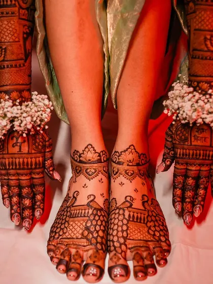 A full view of the bride's hands and feet, showing a coordinated design of peacocks and traditional patterns.