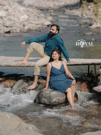 A lovely shot of a couple sitting by a small cascade, dipping their feet in the water, capturing a moment of peaceful connection.