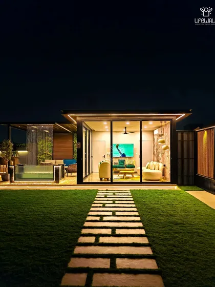 A wide shot of a completed project, showing the glass house, the glass-walled pool, and the stone pathway leading through the artificial grass lawn.