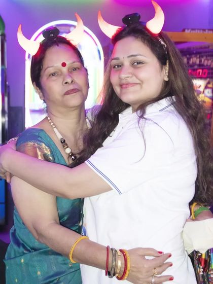 Two women sharing a hug at a party, wearing fun light-up horn headbands. We capture the fun and playful side of your events.