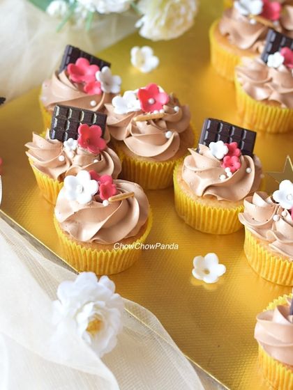 A detailed close-up of the choco-vanilla cupcakes, showing the texture of the frosting and the delicate sugar flowers.