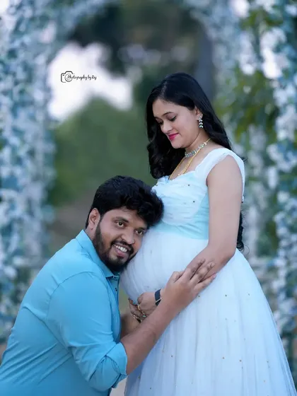 A heartwarming pose where the father-to-be listens to the baby bump. This shot, taken under our white floral arch, is a favorite for capturing the couple's connection.