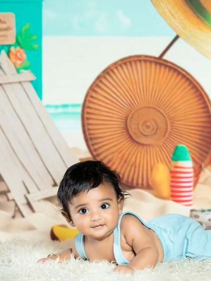 A happy baby enjoying tummy time on a beach-themed set.