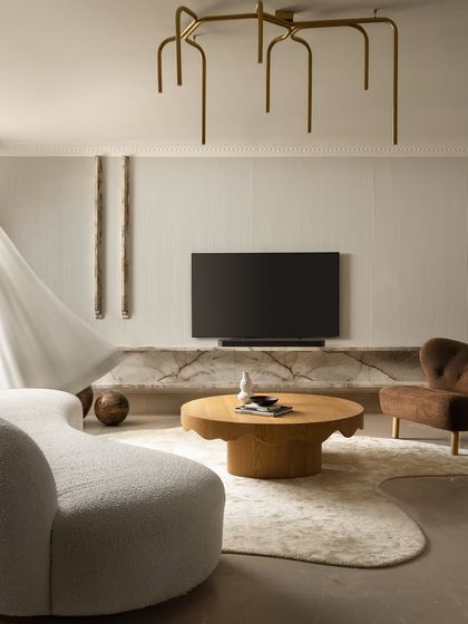 Another perspective of the Ecru Maison living room, highlighting the interplay of the curved sofa, the organic-shaped rug, and the solid oak coffee table. The design balances soft forms with the linear texture of the fluted wall and the drama of the marble console.