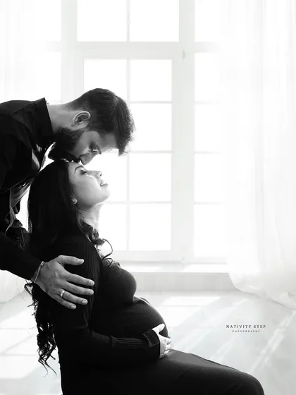 An incredibly tender and intimate black and white portrait. The soft window light and the couple's gentle embrace create a truly emotional image.