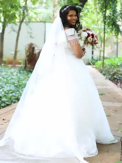A full-length shot of the bride in a beautiful garden setting. Her princess-style gown and long veil are complemented by a classic updo and radiant makeup.