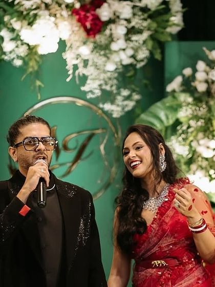 The couple enjoying their celebration against the elegant green and white backdrop. The contrast of their vibrant attire with the sophisticated decor highlights how the design serves to make the clients the center of attention.