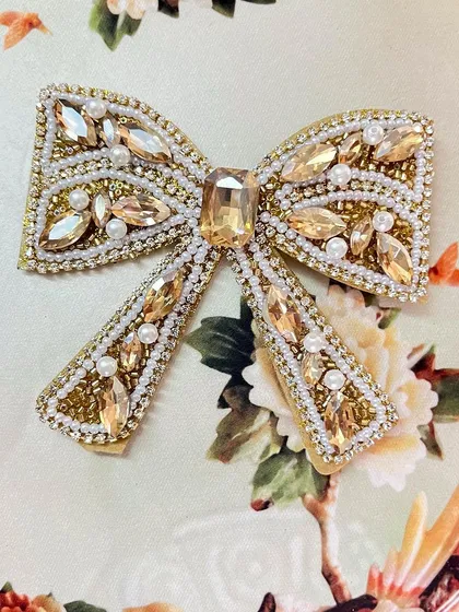 The gold embellished bow adds a touch of warmth and luxury, perfect for a wedding or festive occasion.