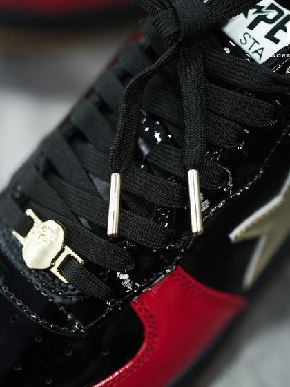 A macro shot of the gold Bape head lace dubrae and metallic-tipped laces on the Bapesta Dubai Anniversary edition.