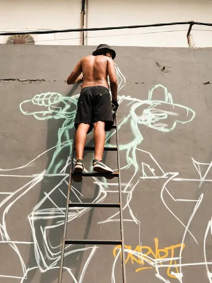 A process shot of the "Attitude Adjustment" mural. Up on the ladder, sketching out the character and the big piece. It's all about that initial outline.