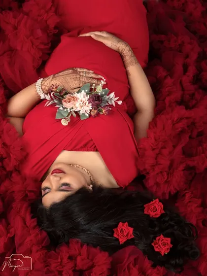 The serene beauty of motherhood is perfectly captured in our 'Sleeping Pose' setup. This artistic shot, with the mama-to-be enveloped in a sea of rich red fabric, is a powerful and elegant portrait of tranquility and love.