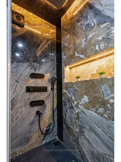 A close-up of the shower area, showcasing the wall-mounted jets and hand shower. The warm LED strip lighting in the niche adds a cozy and inviting ambiance.