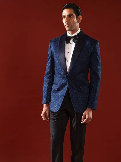 A full-length view of our classic navy blue textured tuxedo. The impeccable fit and the elegant drape of the fabric demonstrate our mastery of formal tailoring, creating a silhouette that is both powerful and refined.