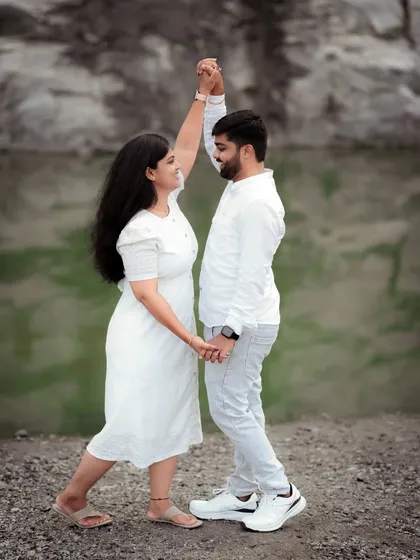 A couple shares a dance, lost in their own world. This pre-wedding shot, with its simple white outfits and natural backdrop, focuses purely on their connection.