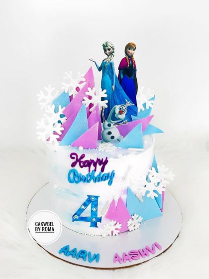 A Frozen-themed cake for twins Aarvi and Aashvi. The design features Elsa, Anna, and Olaf amidst a flurry of icy shards and snowflakes.