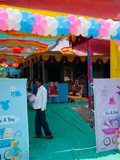 The entrance to a large outdoor baby shower, featuring a gender reveal theme with pink and blue banners and a balloon arch.