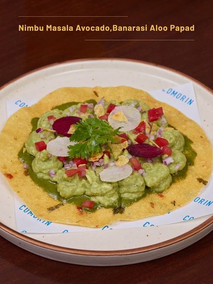 A close-up of our Nimbu Masala Avocado on Banarasi Aloo Papad. It’s a fresh, vibrant, and crunchy snack that’s perfect with a cool drink.