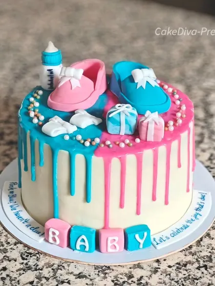 This gender reveal cake is a fun and popular design. It features a clean white finish with both pink and blue chocolate drips, topped with adorable, handcrafted baby-themed fondant elements like tiny shoes and a milk bottle.