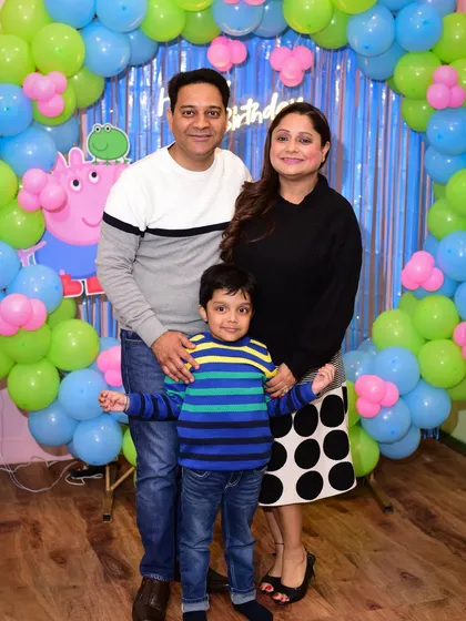 A happy family portrait in front of the Peppa Pig themed decorations.