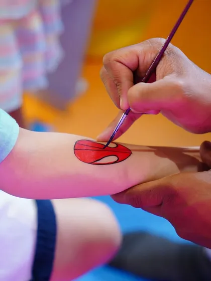 A close-up of our tattoo artist carefully painting a Superman logo. Fun and safe temporary tattoos or face painting are fantastic add-ons that let kids wear their theme with pride.