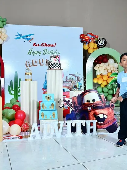 The birthday boy, Advith, posing proudly in front of his amazing 'Cars' themed birthday setup.
