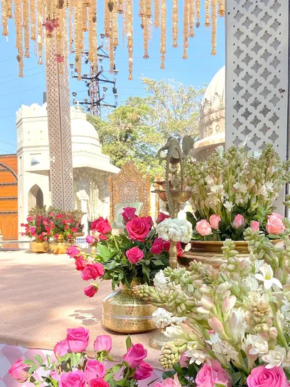 Details from the minimalist wedding mandap. The pillars were adorned with brass matkas and traditional temple accessories, while the ceiling was draped with strings of guldawari, lotus, and roses.