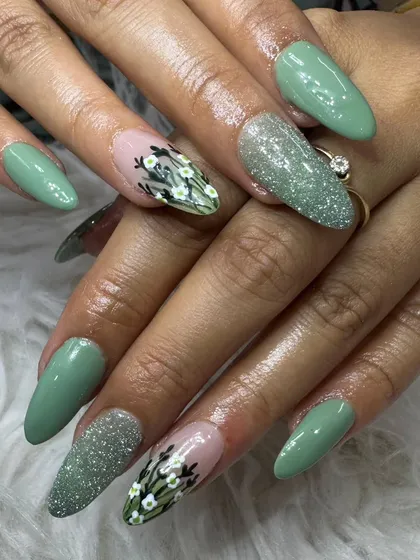 This elegant set combines solid sage green nails with glitter and floral accents. The delicate white flowers were meticulously hand-painted over a nude base.