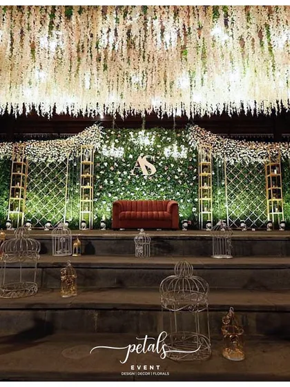 For receptions, I love designing spaces that feel both glamorous and inviting. This stage features a lush green fern wall dotted with flowers, a cascading floral ceiling, and a comfortable velvet sofa, creating a luxurious yet relaxed setting for the couple to celebrate.