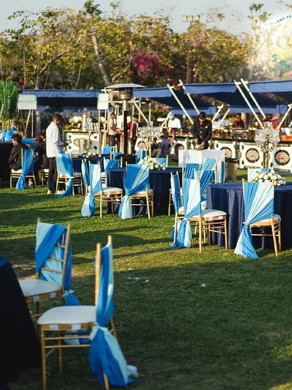 An overview of the outdoor Mehendi-Sangeet setup, showing the elegant table arrangements and the vibrant blue color scheme.