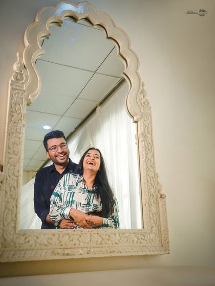 A moment of shared, uninhibited laughter captured in a mirror's reflection. This creative composition adds a unique and personal touch to your pre-wedding story.