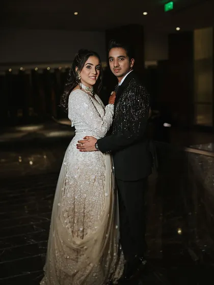 A classic couple portrait from a Sangeet ceremony. The bride's shimmering white gown and soft, elegant makeup create a look of modern sophistication.
