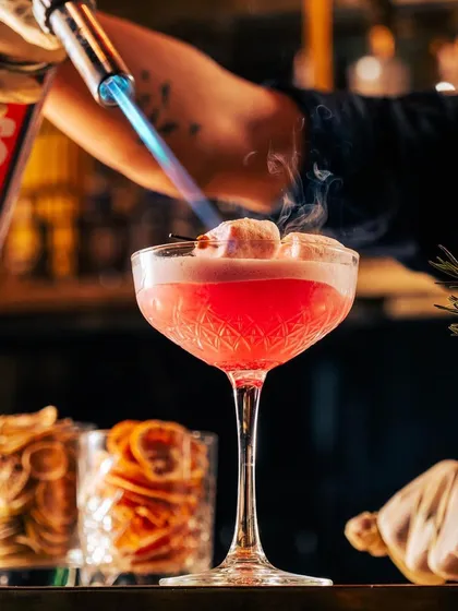 A cocktail with a fiery finish. Our mixologist torches marshmallows atop this pink drink, caramelizing the sugar and adding a smoky depth to the sweet, whimsical creation.