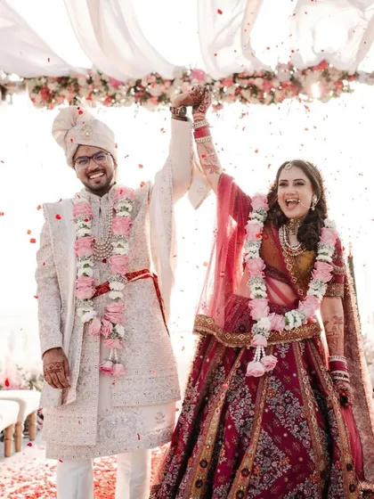 That "just married" feeling, amplified by the sea breeze and golden light of a Goa beach. The couple's joy is palpable as they celebrate under a floral canopy.