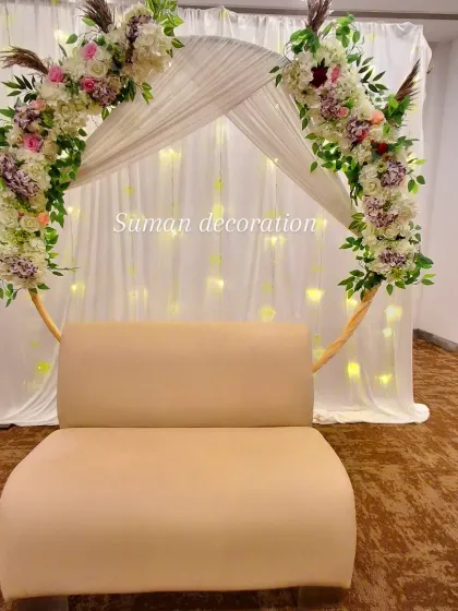 A full view of the elegant floral arch and fairy light backdrop, complete with a sofa for guests to take photos.