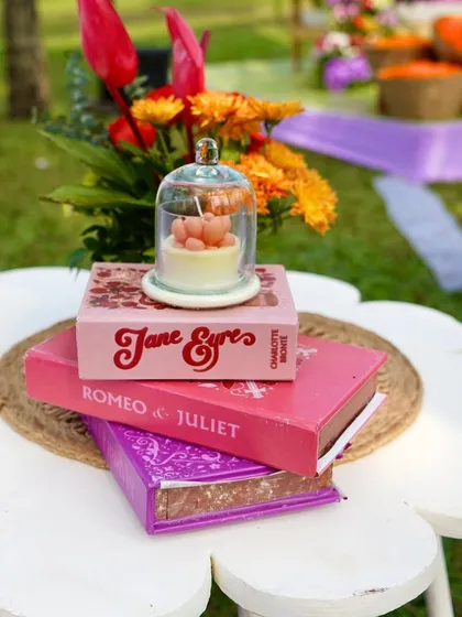 A quirky decor detail from a carnival-themed event, with classic books like 'Romeo & Juliet' used as part of the centerpiece.