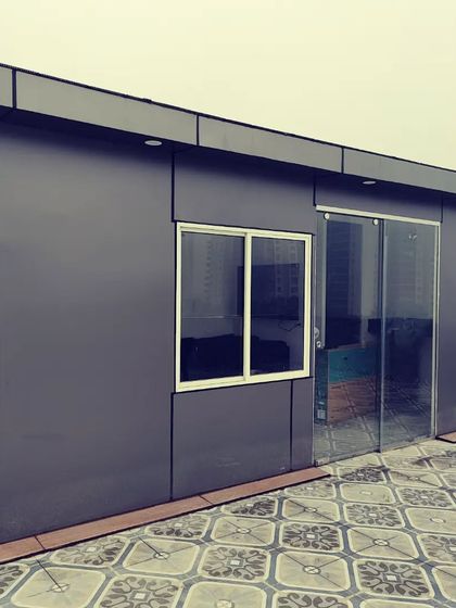 For a clean, contemporary look, we use Aluminium Composite Panels (ACP). This prefab room features dark grey panels and a sliding glass door, creating a sleek and durable exterior.