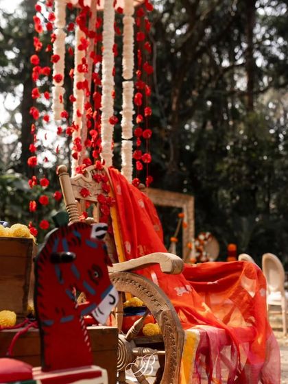 An antique chair and rocking horse are paired with a draped heirloom dupatta and hanging floral strings, creating a photo corner rich with nostalgia and personal history.