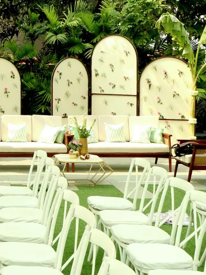 The guest seating arrangement, with elegant white chairs facing a stage framed by custom-printed panels and lush greenery.