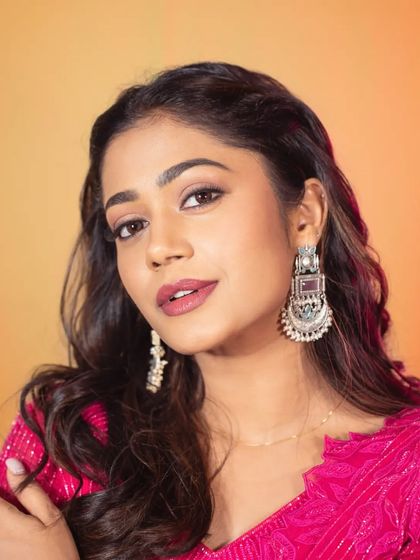 A detailed shot focusing on the silver-toned statement earrings that perfectly complement the bright pink outfit. I believe accessories are the final touch that brings a whole look together.