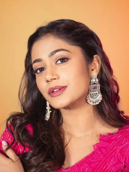 A detailed shot focusing on the silver-toned statement earrings that perfectly complement the bright pink outfit. I believe accessories are the final touch that brings a whole look together.