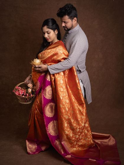 Elegance and tradition come together in this stunning maternity portrait. The vibrant silk saree and the soft flowers create a rich, cultural narrative. The husband gently supports his wife, a beautiful picture of partnership.
