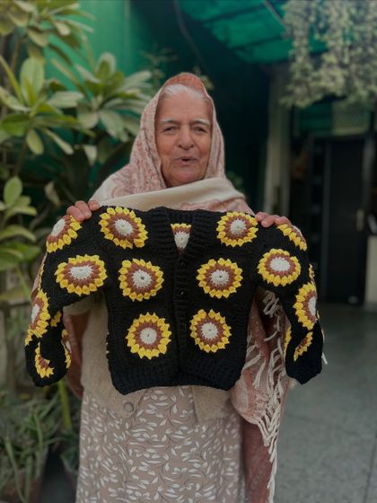 A beautiful sunflower-themed baby cardigan. The dark base makes the yellow and brown granny square sunflowers pop, creating a stunning and unique piece for a stylish baby.