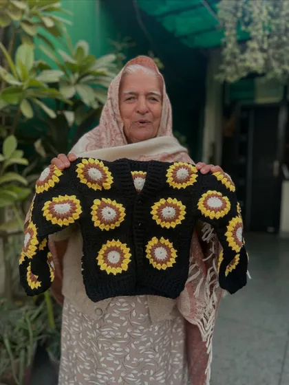 A stylish black cardigan featuring a classic sunflower granny square pattern. This piece combines traditional crochet techniques with a bold, modern look.