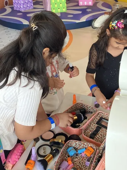 Two friends合作 on a makeover at the pretend makeup station during a party.