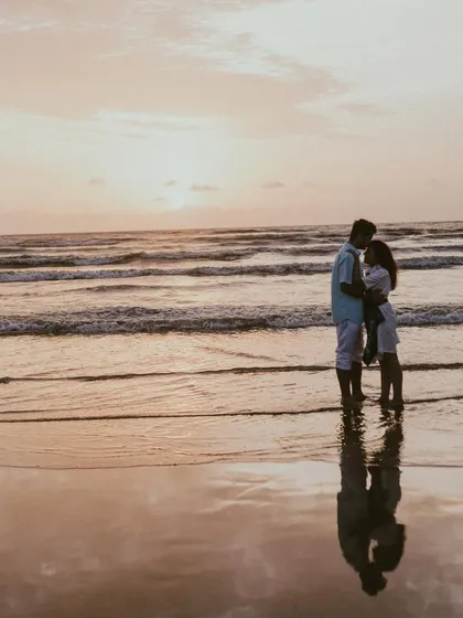 A perfect end to a perfect day. This silhouette shot captures the couple against the sunset, with their reflection shimmering on the wet sand. It's a simple, powerful, and incredibly romantic pre-wedding beach photo.
