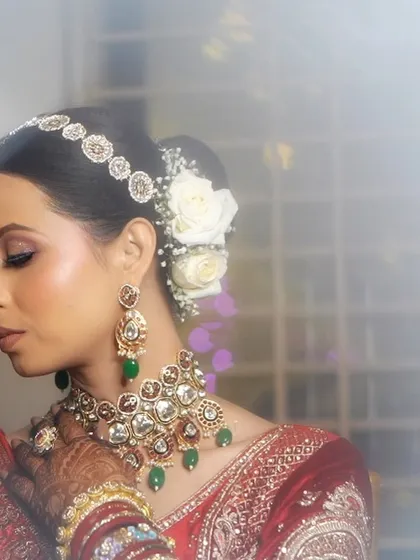 A dreamy, artistic portrait of a bride in her red lehenga. The white roses in her hair add a touch of modern elegance to the traditional look.